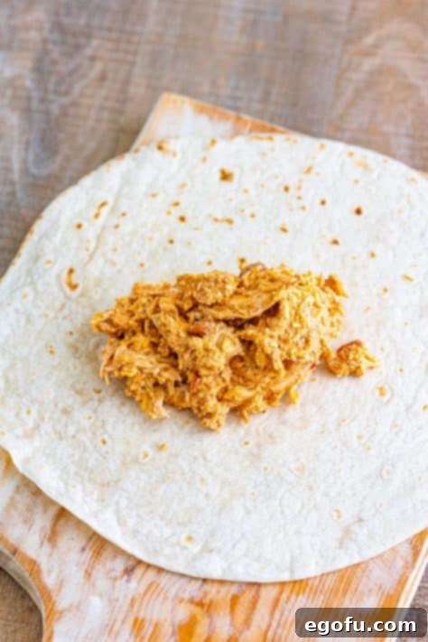 Tortillas prepared with a generous amount of chimichanga filling centered on each, laid out on a clean surface.