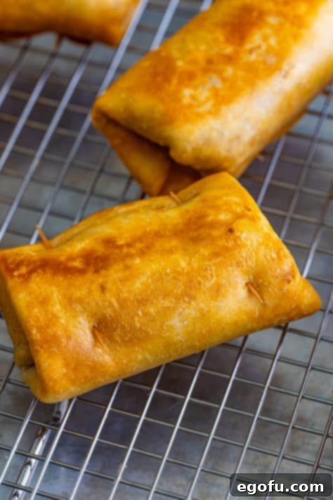 Crispy chimichangas arranged on a wire rack for optimal drainage and to maintain crispness, ready for serving.