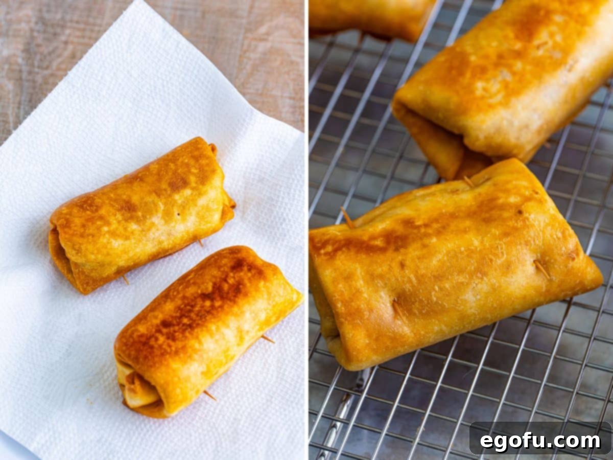 Several perfectly golden-brown fried chimichangas resting on a plate lined with paper towels to absorb excess oil, showcasing their crispy texture and readiness to be served.