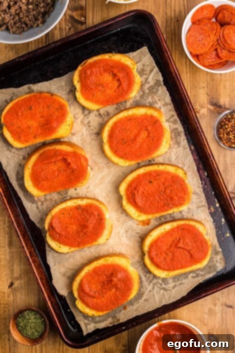Pizza sauce on Garlic Bread Texas Toast slices, arranged on a baking sheet.