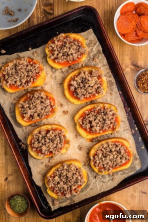 Cooked sausage and pizza sauce layered on top of Texas Toast with garlic butter, all on a parchment lined sheet.