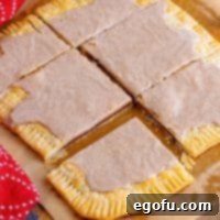 A whisk in a bowl of powdered sugar, cinnamon, vanilla, and milk, creating a smooth glaze.