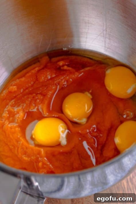 Decadent Pumpkin Pie Cake 10 A bowl with pumpkin pie mix and eggs being mixed, showing the initial wet ingredients.