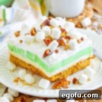 A small piece of Pistachio Layered Dessert on a dessert plate with more mini marshmallows, ready to be served.