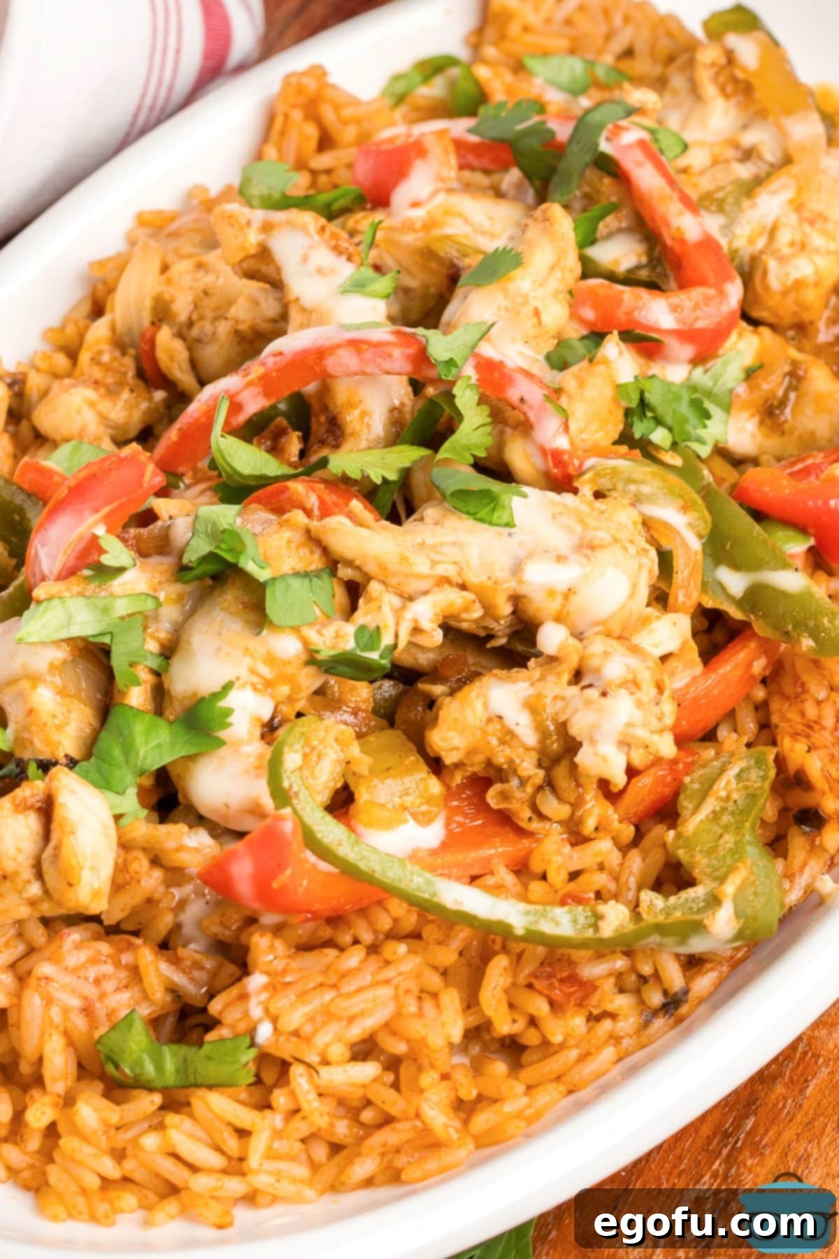 Effortless Arroz con Pollo 2 A large serving platter of Arroz con Pollo, featuring seasoned chicken, rice, and colorful vegetables, topped with creamy queso.