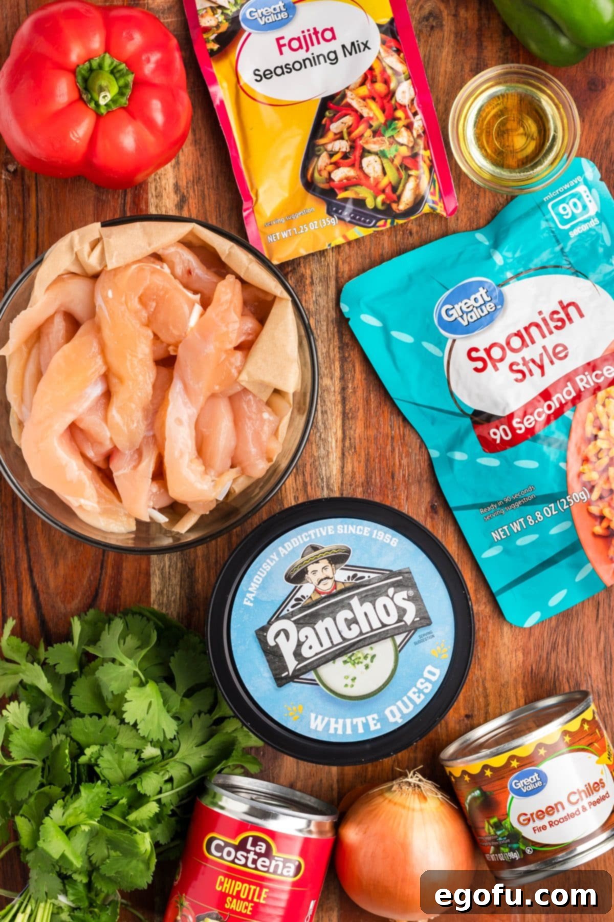 Effortless Arroz con Pollo 4 A spread of fresh ingredients for Arroz con Pollo: sliced chicken, colorful bell peppers, oil, fajita seasoning, chipotle sauce, green chiles, white queso, Spanish rice, and fresh cilantro.