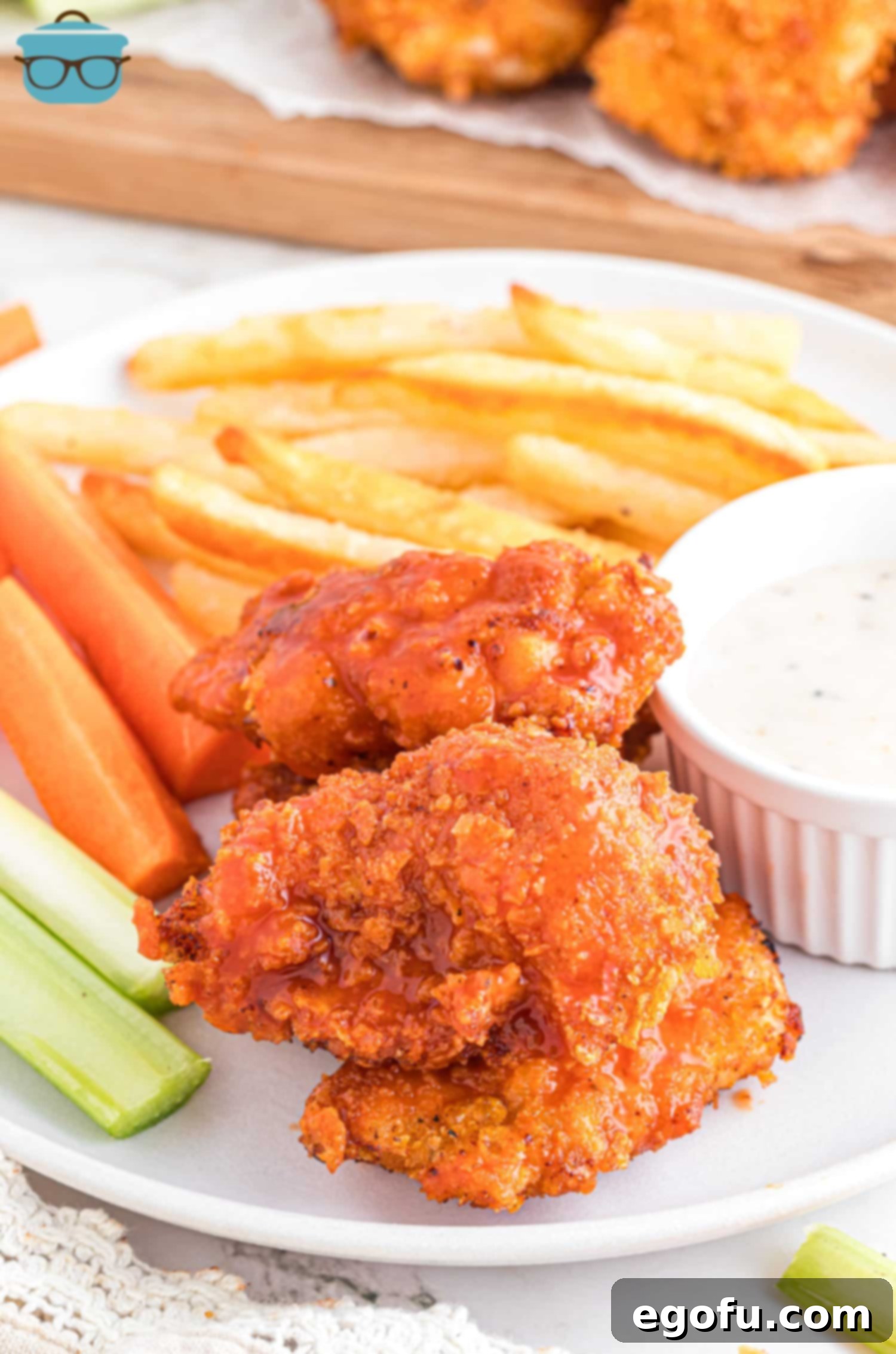 A small pile of Boneless Chicken Wings with some celery, carrots, fries, and dip.