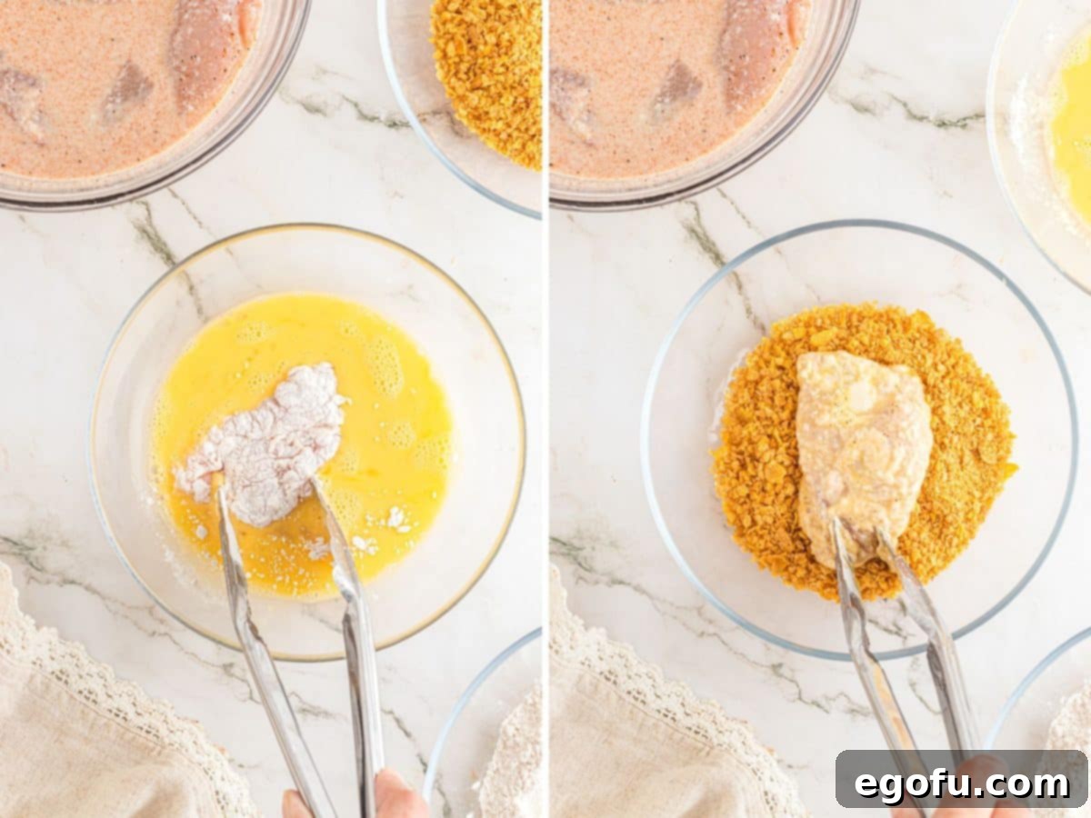 Tongs dipping flour coated chicken in an egg mixture and into a cornflake crumb mixture. 