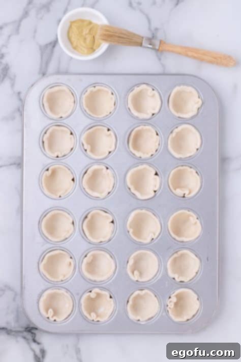 Circular pieces of puff pastries in a muffin tin.