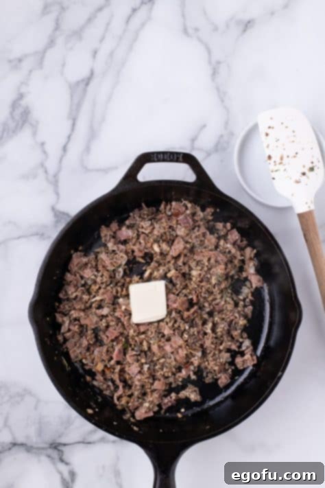 Butter and salt and pepper being added to a mushroom mixture in a skillet.