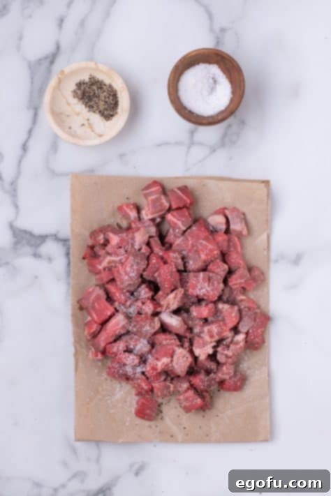 Cubed beef tenderloin on a cutting board.