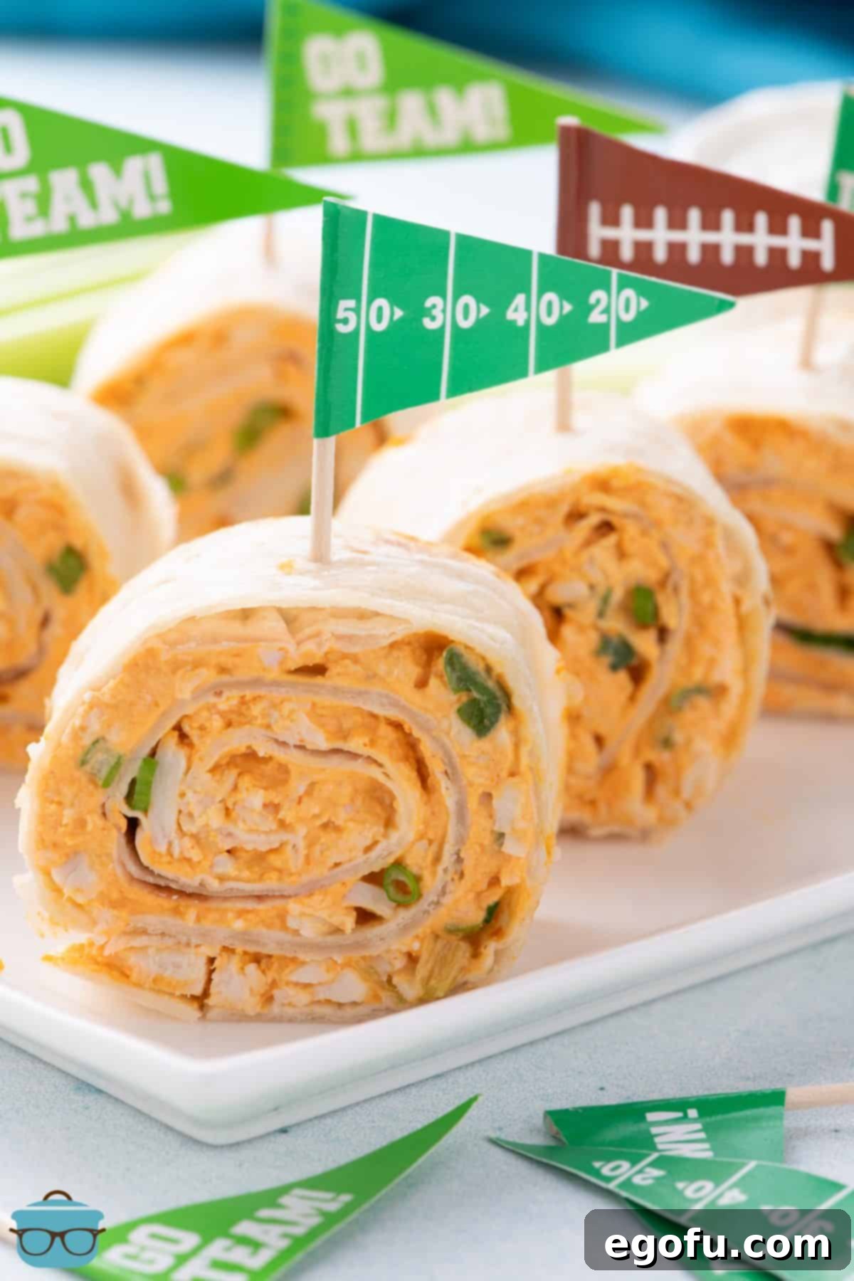 A line of Buffalo Chicken Pinwheels and one with a football field toothpick.