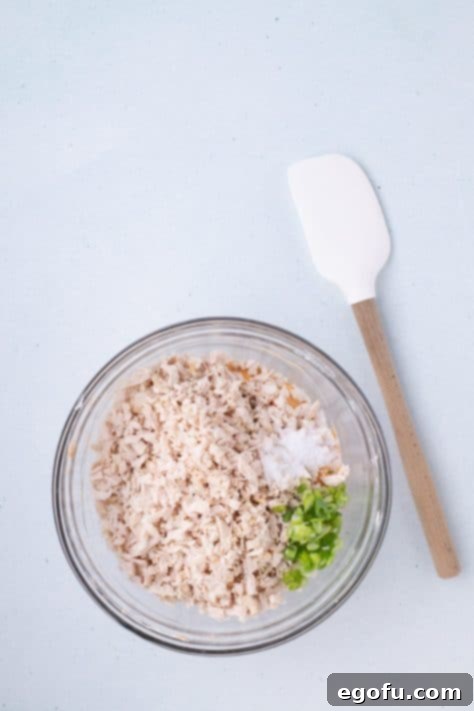 Chicken, green onions, and salt being added to a buffalo mixture.