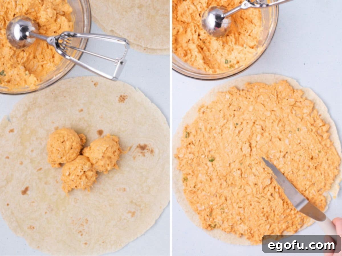 The buffalo chicken mixture on a tortilla being spread out into a thinner layer.
