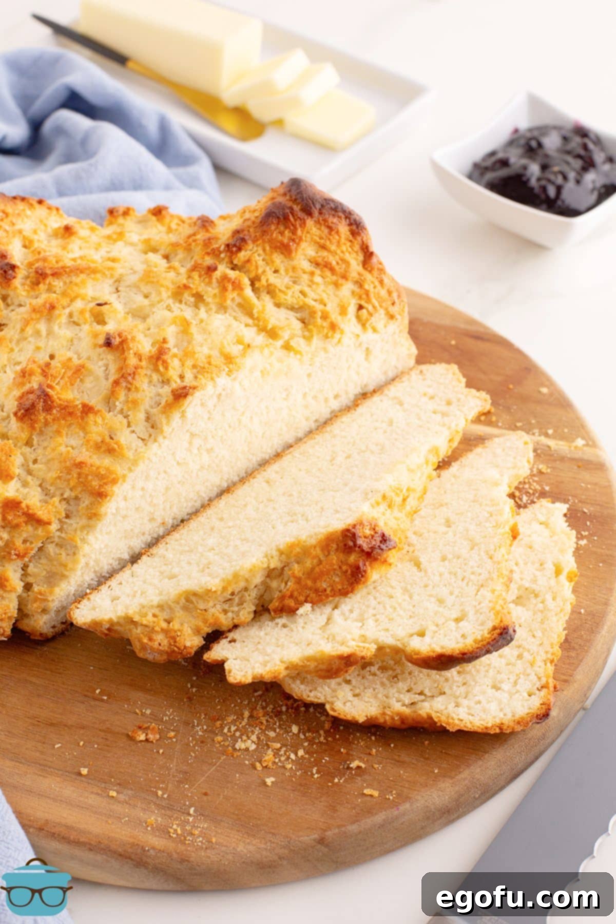 Celtic Loaf 2 A perfectly golden, crusty loaf of homemade Irish Soda Bread, with several slices removed revealing its soft interior, resting on a rustic wooden board, ready to be enjoyed.