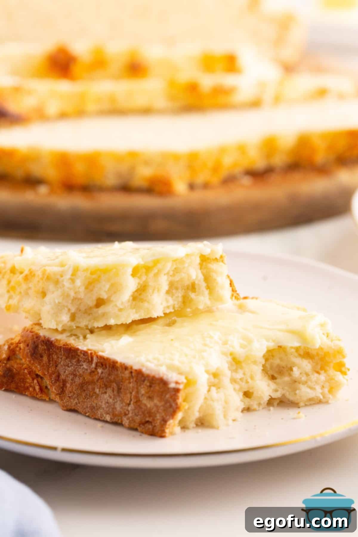 Celtic Loaf 8 A close-up of several slices of warm Irish Soda Bread, generously slathered with butter, with one slice showing a delightful bite taken, resting invitingly on a pristine white plate, promising pure comfort.