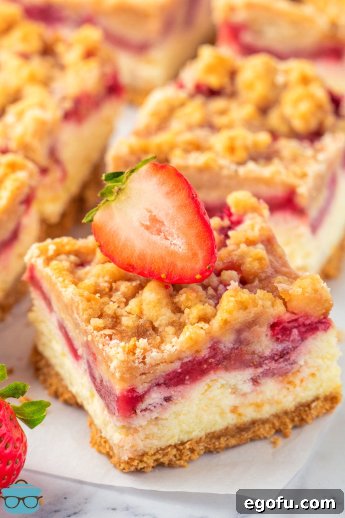 Luscious Strawberry Crumble Cheesecake Squares 2 A beautifully arranged stack of freshly baked Strawberry Crumble Cheesecake Bars, showcasing the distinct, mouth-watering layers of graham cracker crust, creamy cheesecake, juicy strawberry filling, and a golden crumble topping.