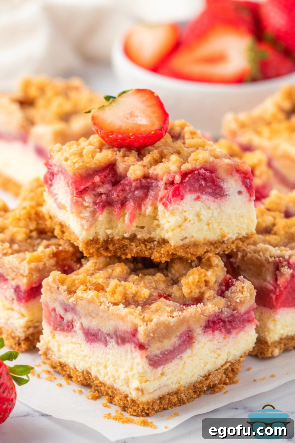 Luscious Strawberry Crumble Cheesecake Squares 13 A few perfectly cut Strawberry Crumble Cheesecake Bars arranged on a serving plate, highlighting their delightful layers and golden crumble topping, with one bar showing a bite missing.