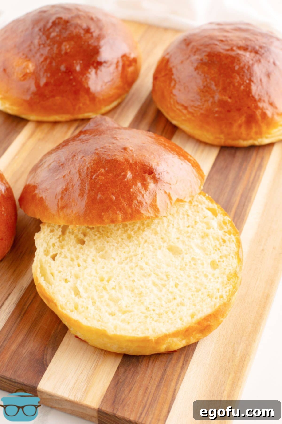 Golden Buttery Brioche Buns Fresh From Your Oven 2 A homemade Brioche Bun split open on a wood board, showcasing its soft interior.