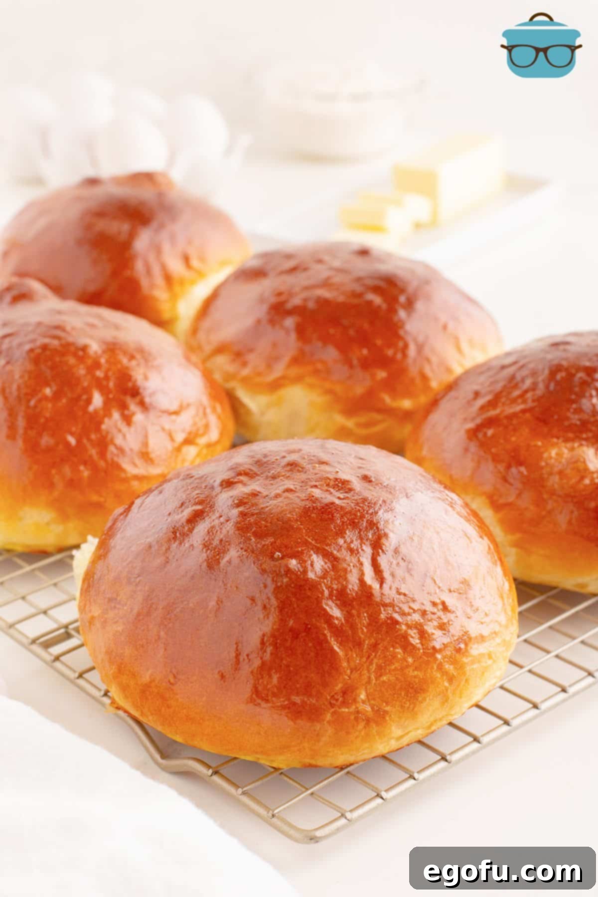 Golden Buttery Brioche Buns Fresh From Your Oven 13 A few freshly baked Homemade Brioche Buns resting on a cooling rack, ready to be served.
