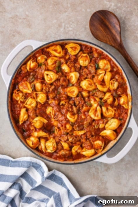 Tortellini with sauce, veggies, and spices in a skillet.