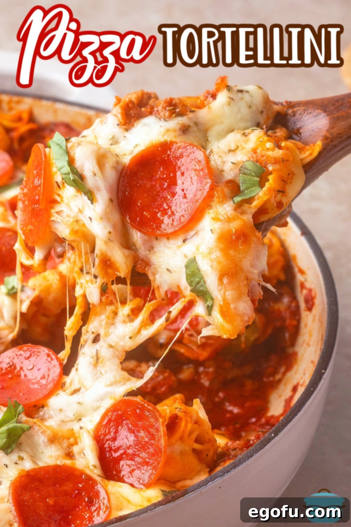 A pot with a bunch of Pizza Tortellini and a scoop of it being held above the pot, showing the melted cheese and pepperoni.