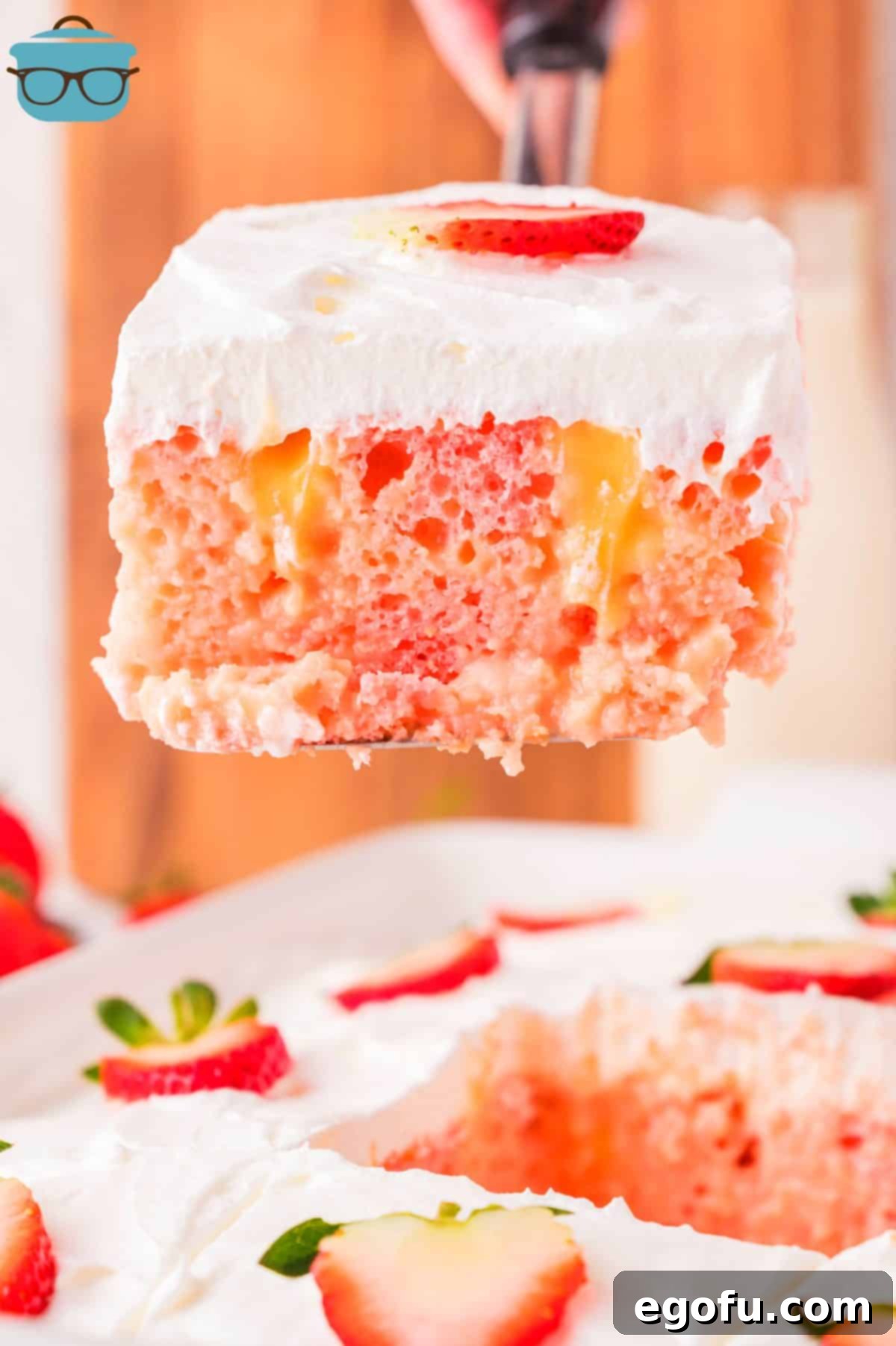 Velvety Strawberry Poke Cake Bliss 2 A serving utensil holding a slice of Strawberry Pudding Poke Cake above the rest of the baking dish, showcasing its layers.