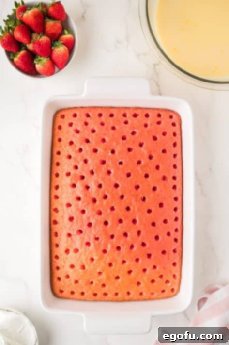 Velvety Strawberry Poke Cake Bliss 13 A baked cake with holes poked into it, ready for pudding.