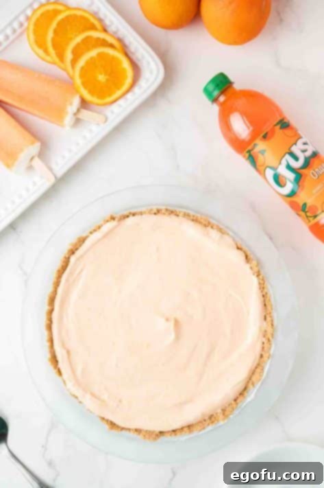 Zesty Orange Cream Pie 16 An orange creamsicle pie covered with plastic wrap, chilling in the freezer.