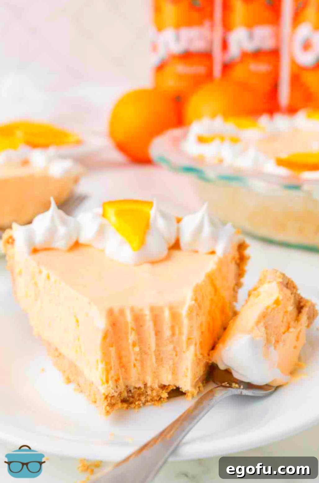 Zesty Orange Cream Pie 9 A dessert plate with a slice of Orange Creamsicle Pie, showing a bite taken out and the fork holding the bite, inviting a taste.