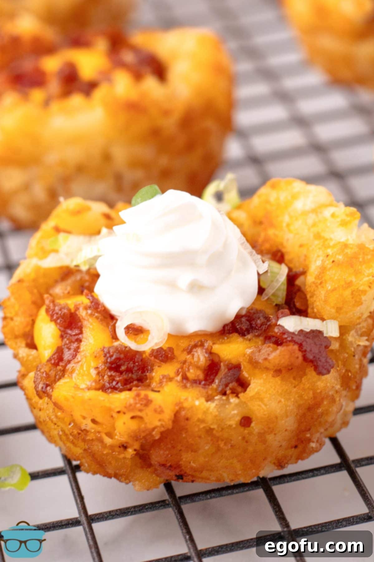 A few freshly baked Loaded Tater Tot Cups, golden and cheesy, cooling on a wire rack.