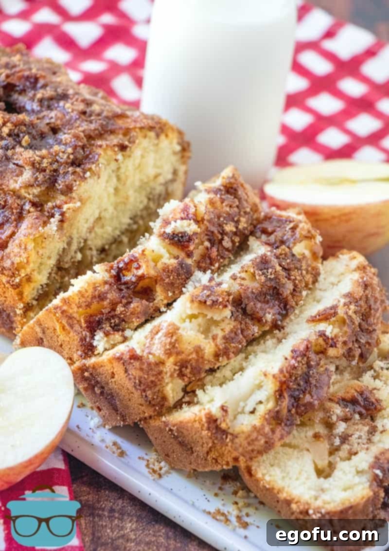 Sliced Homemade Apple Pie Bread on a long tray with milk and sliced apples pictured in the background.