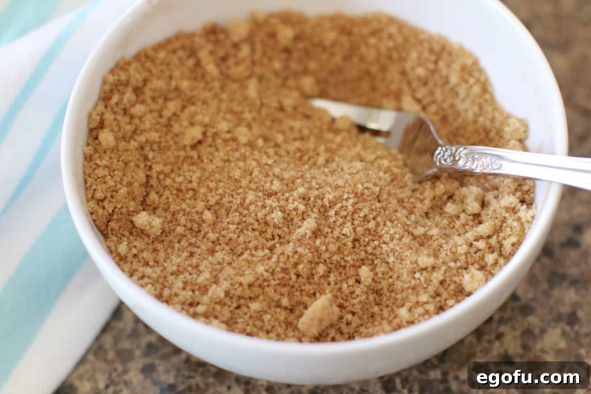Brown sugar and ground cinnamon mixed together with a fork in a small white bowl.
