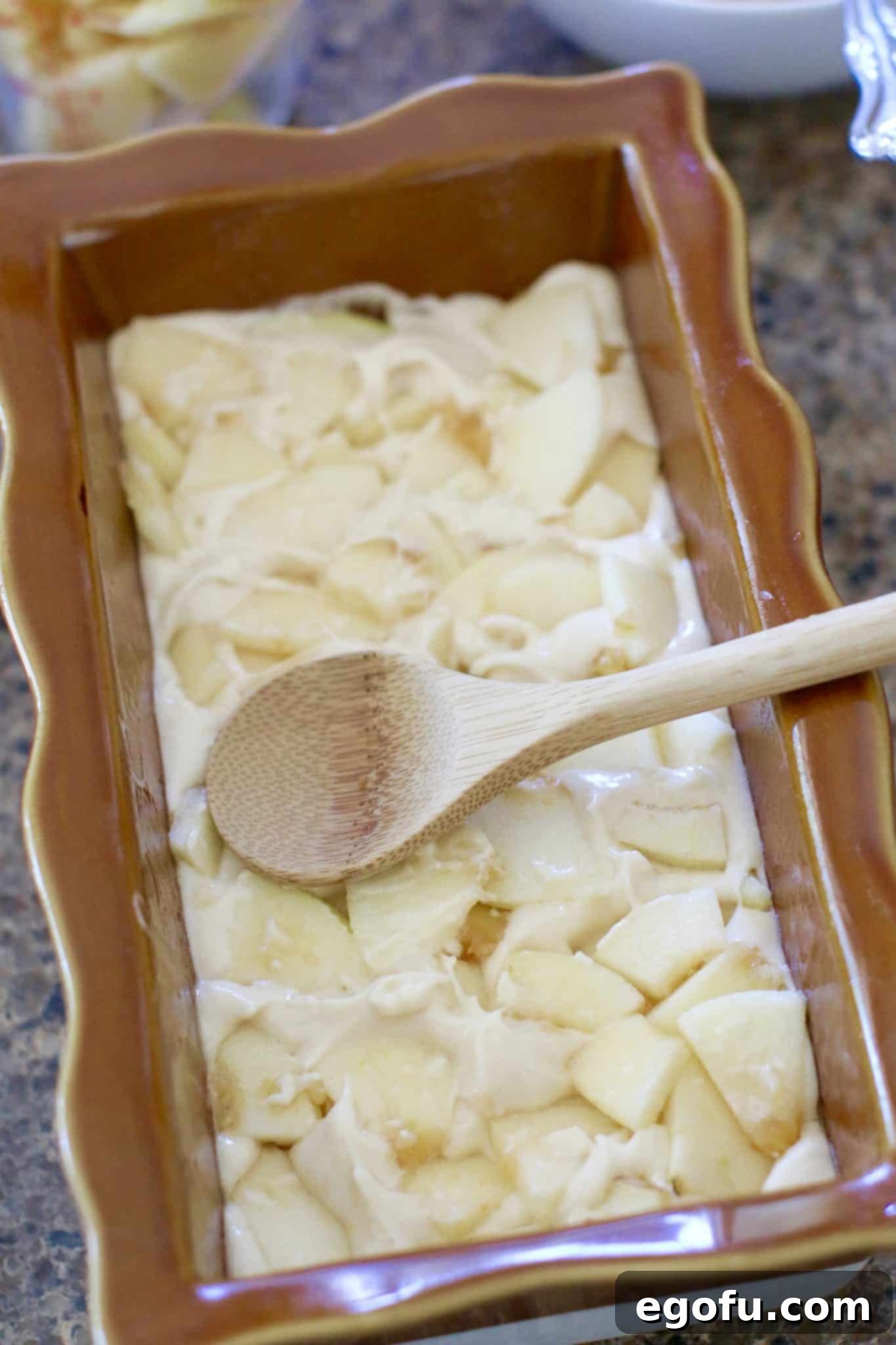 Bread batter poured into the bottom of a bread pan and topped with chopped apples.