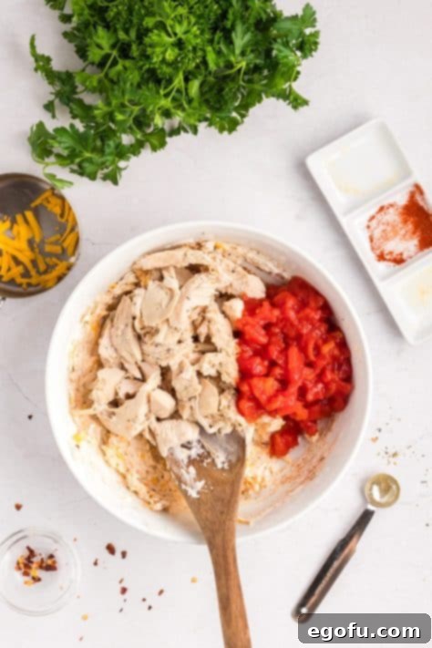 Savory Chicken Stuffed Bell Peppers 13 Chicken and tomatoes sitting on a mixture in a bowl.