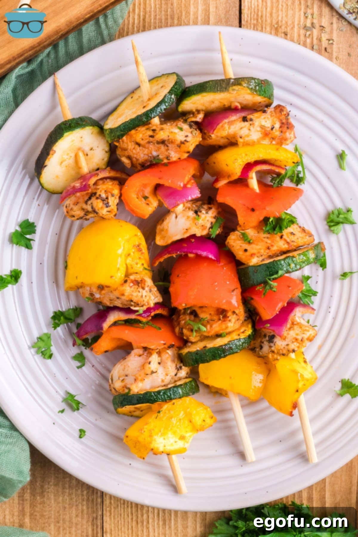 Looking down on a beautifully presented plate of perfectly baked chicken skewers, garnished with fresh parsley.