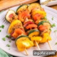 Looking close up on three Chicken Skewers on a plate, garnished with herbs.
