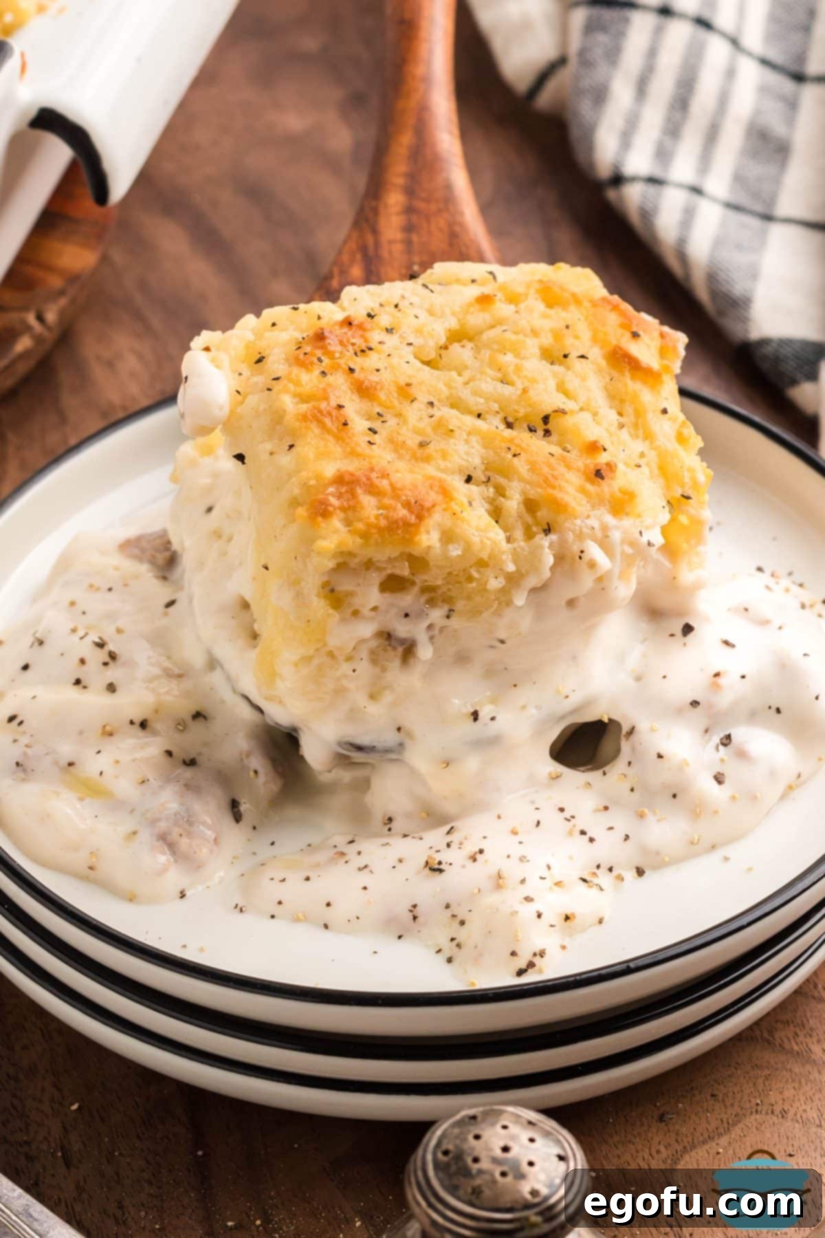 A plate with a ton of sausage gravy and a butter swim breakfast biscuit.