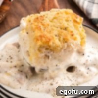 Looking down on a Sausage Gravy Butter Swim Biscuit with plenty of gravy on a plate.