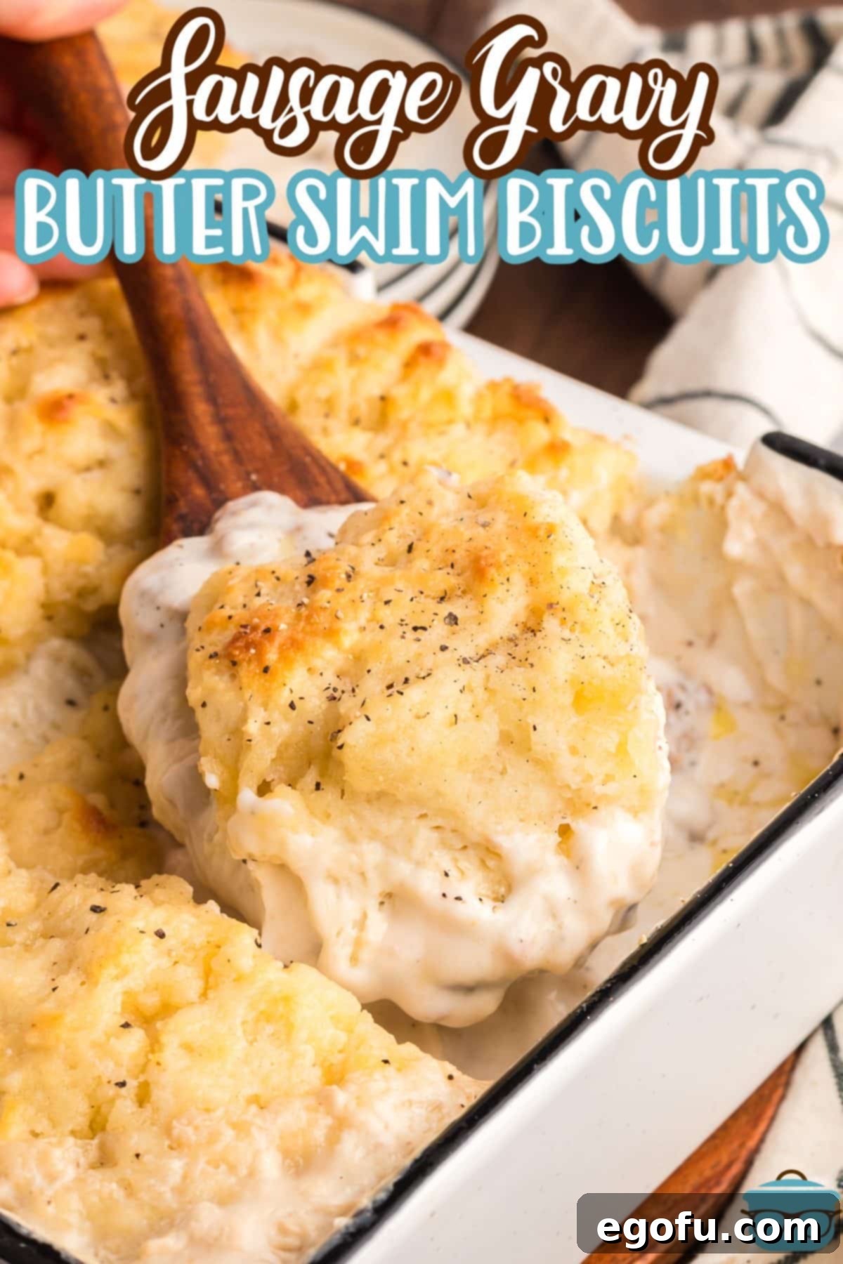 A wooden spoon getting a scoop of Sausage Gravy Butter Swim Biscuits.