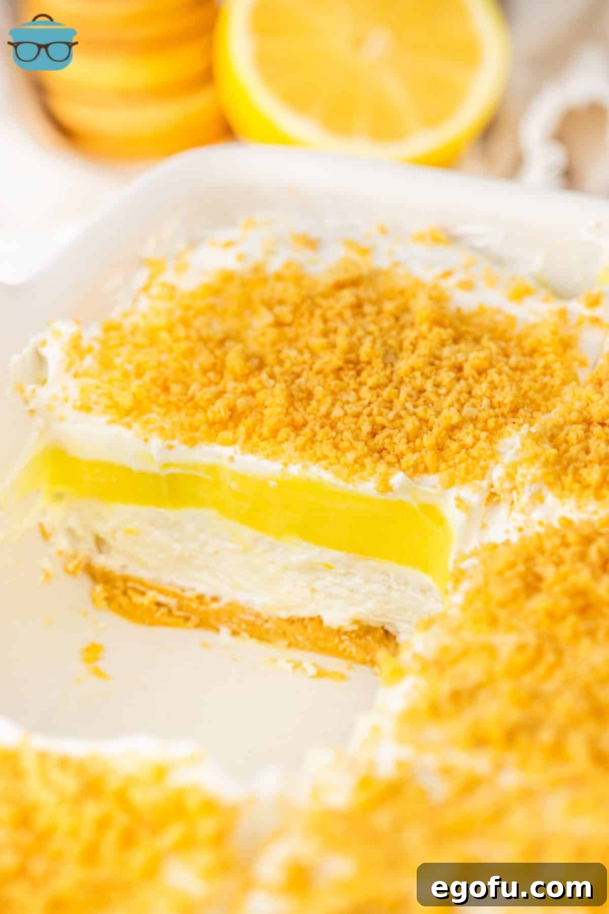 A baking dish missing a slice of Lemon Lush Delight, showing its distinct layers.