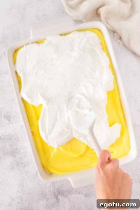 Cool Whip being spread out over the lemon layer.