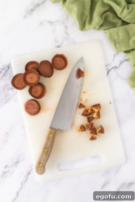 A knife chopping Reese's cups on a cutting board.
