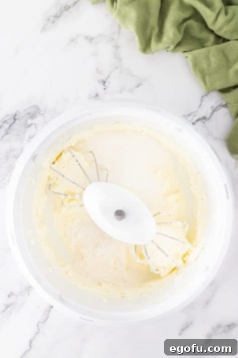 Cream cheese, sugar, and flour being mixed together in a mixing bowl.