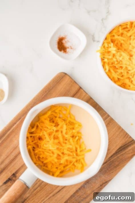 Freshly shredded cheese and spices being added to the creamy sauce base.