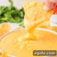 Close up looking at a chip being dipped in Nacho Cheese.