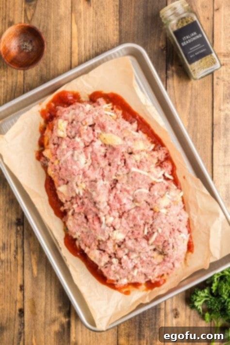 Grandma's Secret Italian Meatloaf 13 A moist meatloaf on top of marinara sauce on a baking sheet.