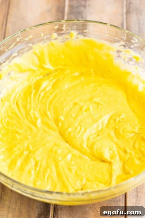 Tropical Coconut Bake 10 A large bowl with cake mix, pudding mix, water, half of the coconut flakes, oil, and eggs making a batter.