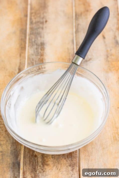 Tropical Coconut Bake 13 A whisk in a bowl of glaze.