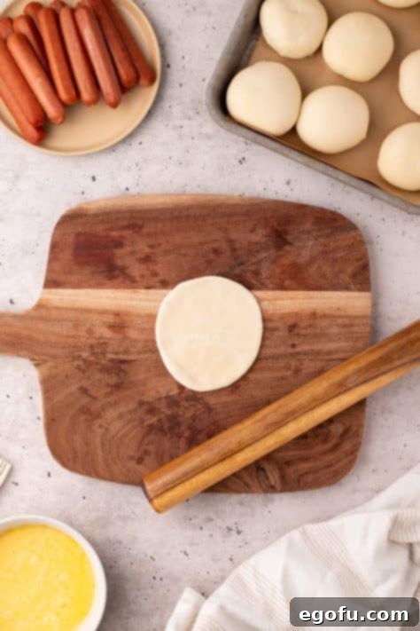 Hearty Texas Sausage Kolaches 12 A dinner roll dough piece rolled out on a wooden board.